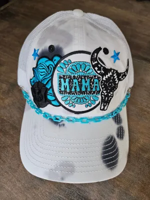 Tie dye trucker hat in black and turquoise with "mama", bullhead, and roses patches.